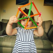 2 year old girl holding a hexagon shape made from lollipop sticks