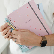 person holding three ivf journey planners, the top copy is the pink polka dot version