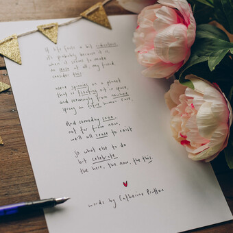 Flat lay of a poem by Catherine Prutton, displayed with tiny bunting and peonies