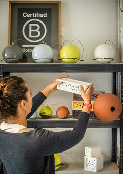 Lady in the Green&Blue office holding bee brick with other products arranged behind on shelves