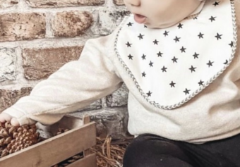baby boy wearing a star bib sitting and playing