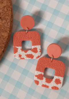 Coral pink textured polymer clay earrings with a cow print pattern