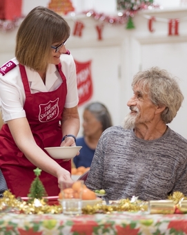 A Salvation Army volunteer serves Christmas dinner to someone experiencing homelessness.