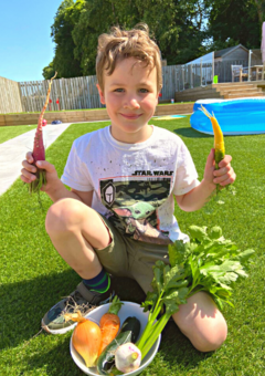 Proud young boy holding home grown vegetables