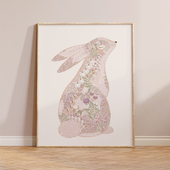 Pink floral bunny art print in a light wood frame leaning on a wall