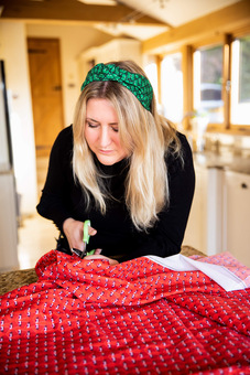 Kate Whyley cutting a large piece of red designer fabric