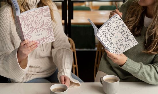 Two people sat at a kitchen island, each with a personalised planner in hand.