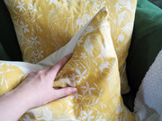 Hand squeezing yellow floral cushion