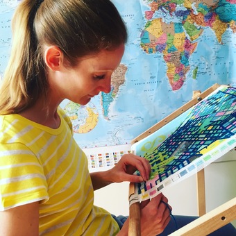 Hannah Bass needlepoint stitching a tapestry city map kit