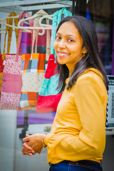 Founder Priya Velusami in front of a selection of upcycled Tote bags
