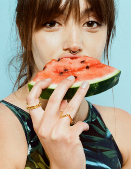 Girl eating watermelon with gold rings and blue background