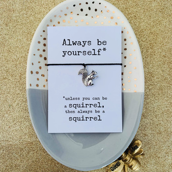 black cord wish bracelet mounted on white card, text reads always be yourself, unless you can be a squirrel, then always be a squirrel